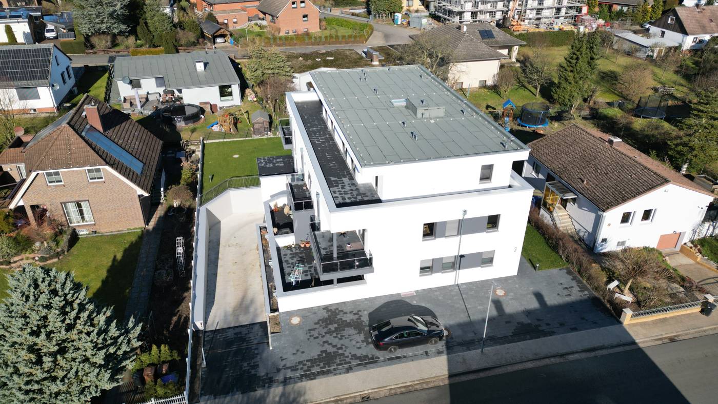 Mehrfamilienhaus Schwülper: weißer Neubau mit Staffelgeschoss und Balkonen